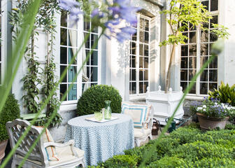 Zeer verzorgd terras met ronde tafels in zeer mooi verzorgde tuin.