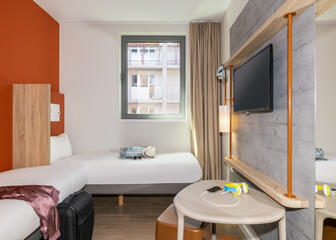 Tweepersoonskamer met oranje muur en TV