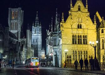 Zicht op Sint-Niklaaskerk en Belfort vanop de Sint-Michielsbrug met avondverlichting.