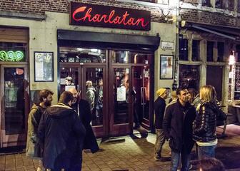 Sfeerbeeld nachtleven Gent. Voorgevel Charlatan met een 10-tal mensen voor de deur, aan het babbelen en aan het roken.