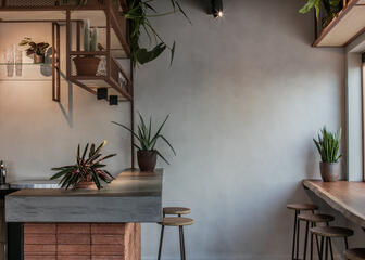 interieur van een restaurant met veel planten, een houten tafel en een stenen bar