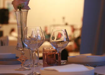 gedekte tafel met glazen, borden ,bestek, vaas met bloem in