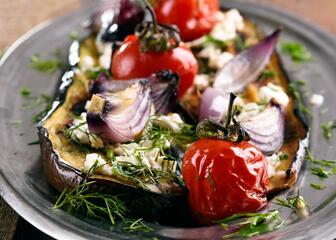 een bord met een aubergine gevuld met paprika, ajuin en kruiden