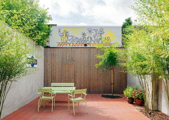 terras galerie rufus, groene tafel met 2 stoelen en een bankje, houten achterwand, bomen en planten