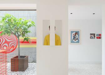 witte kamer met schilderijen, een raam dat naar buiten kijkt met een plant op kiezelstenen