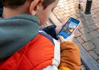 Jongen leest de volgende opdracht van de draakje Fosfor zoektocht op een smartphone