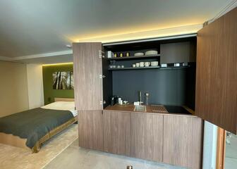 studio with double bed on the left and kitchenette in brown colour on the right
