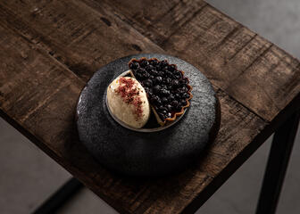 vanilla and blueberry dessert on a grey plate