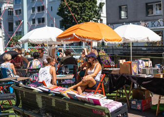 Mensen op een zonnig terras aan de Boekenmarkt