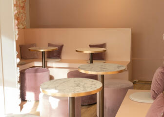 Zicht van op de eerste verdieping: tafeltjes en zitbanken in roze en wit