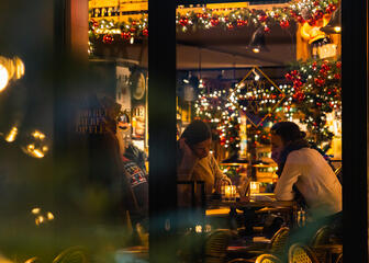 Paar an einem Tisch mit Weihnachtsbeleuchtung am Fenster