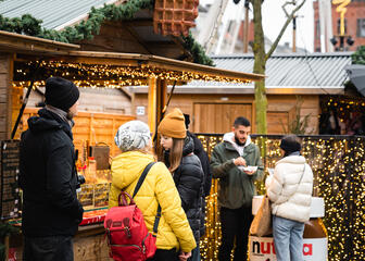 Gente comiendo algo en el mercado navideño