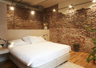 Habitación con cama doble colocada contra una pared de ladrillos