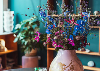 Joyas sobre una mesa con un jarrón de flores