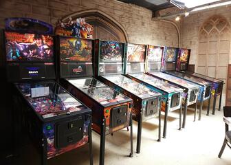 7 pinball machines in a row against a wall