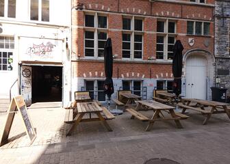 street view of terrace with 6 picnic benches in front of brick façade