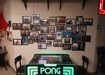 Pong table with 2 chairs against a wall full of pictures