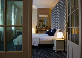 Suite with double bed, blue carpet and beige walls