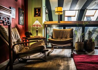 Coin salon avec 2 fauteuils, sol en bois et plantes, lampes de table et cadres