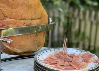 leg of ham in holder next to a plate with slices of raw ham