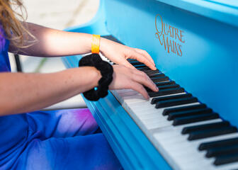 Mädchen spielt ein blaues Klavier