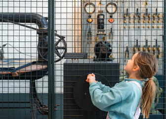 Junges Mädchen dreht das Steuerrad einer alten Maschine im Industriemuseum in Gent