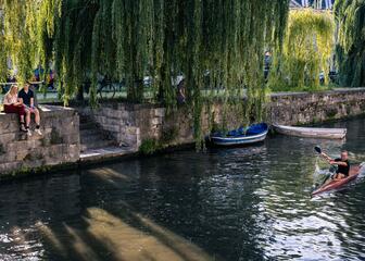 Besucher und Bewohner genießen das schöne Wetter entlang und im Wasser am Prinsenhof in Gent