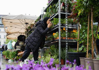 Fatina smells flowers at the flower market on the Kouter in Ghent