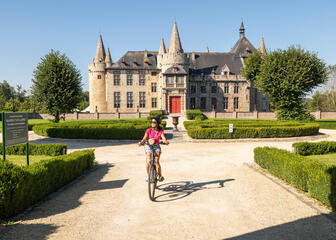 fietser in een kasteeltuin met het kasteel van Laarne in de achtergrond