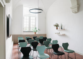 Small hall with lots of light, plants and 5 rows of 4 chairs each