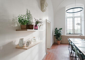 Kleine vergaderruimte met planten en koffietassen op een houten plank, veel lichtinval, 