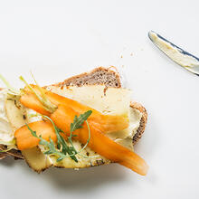 enkele sneden brood met boter, kaas, wortel en rucola, een mes met boter aan