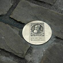 Close-up van een muntje van de muntroute op straat.