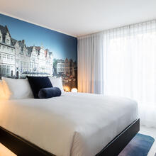 hotelkamer met tweeprsoonsbed, tv en op de muur een foto van gebouwen in Gent
