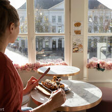 Une femme mange une gaufre avec vue sur le Groentenmarkt
