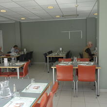 salle à manger blanche avec tables grises et chaises orange