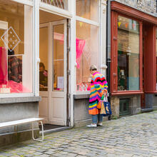 Une femme avec un pull à rayures colorées regarde dans la vitrine d’un magasin de la Serpentstraat à Gand