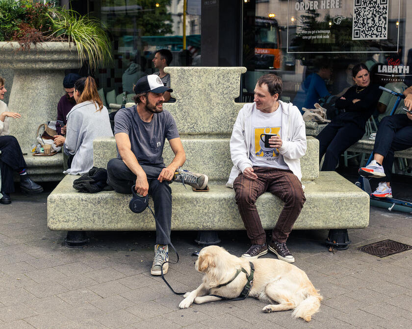Two young men enjoy a coffee at Bar Labath with their dog