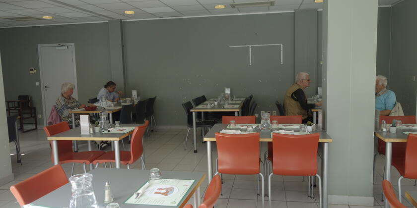 witte eetzaal met witte tafels en oranje stoelen