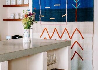 witte keukenblok met open schappen en een wandtapijt met blauwe tinten 