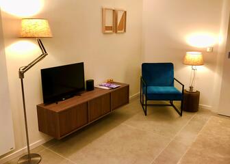 sitting area with blue armchair, brown TV cabinet and flat screen