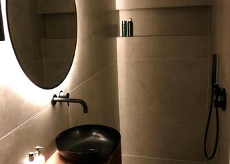 badkamer met wastafel en ronde, verlichte spiegel